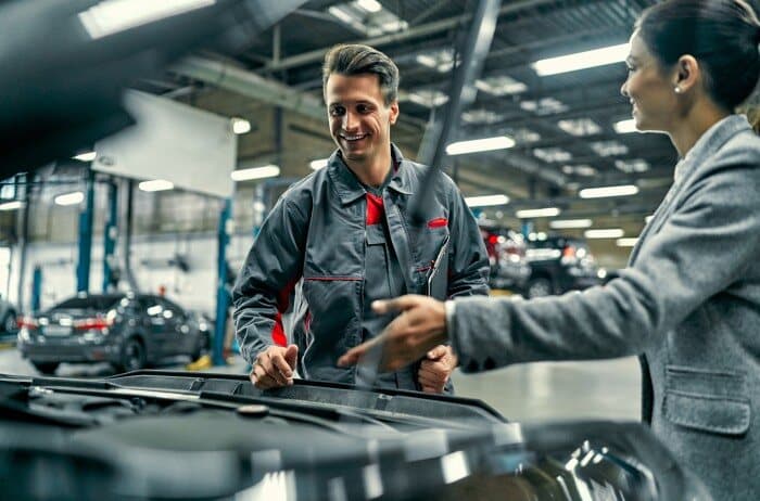 Kfz-Mechaniker berät eine Kundin in seiner Werkstatt